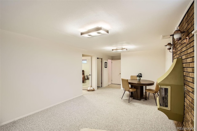 carpeted dining space with baseboards and a brick fireplace