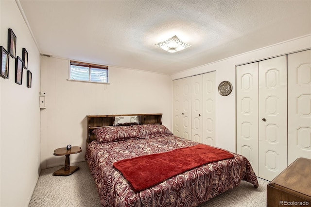 bedroom featuring baseboards, multiple closets, a textured ceiling, and carpet