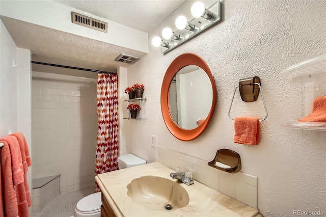 bathroom with visible vents, vanity, a tile shower, and toilet