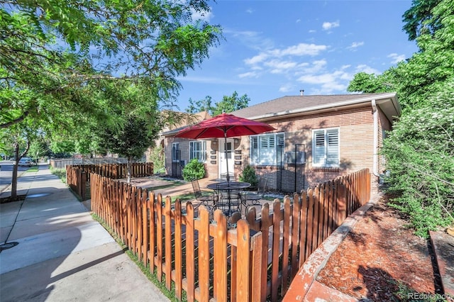 bungalow featuring brick siding, a shingled roof, and fence