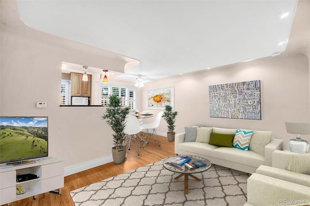 living room with light wood-style flooring, baseboards, and a ceiling fan