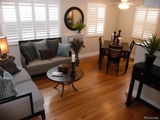 living area featuring light wood-type flooring, ceiling fan, and baseboards