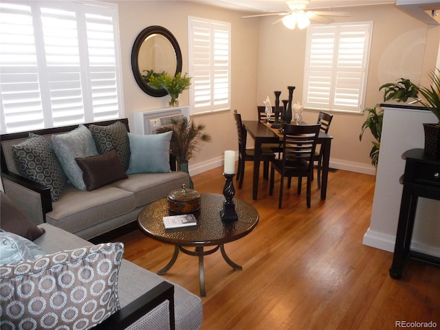 living room with a ceiling fan, baseboards, and wood finished floors