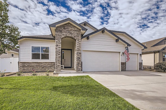 craftsman house featuring an attached garage, a front yard, fence, stone siding, and driveway