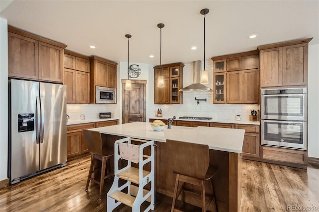 kitchen featuring stainless steel appliances, wall chimney range hood, and brown cabinetry