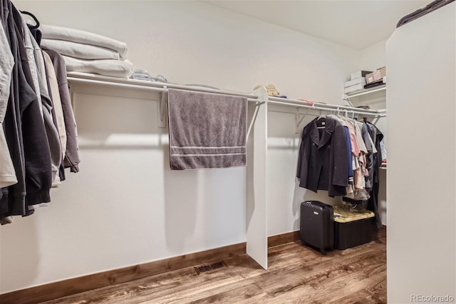 walk in closet with wood finished floors