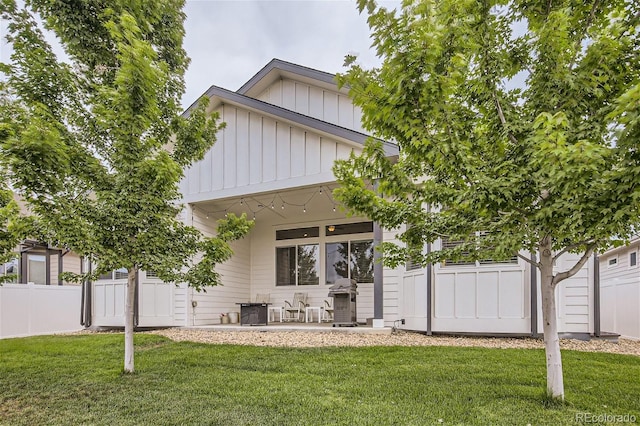 view of front of house featuring a patio area, board and batten siding, a front yard, and fence