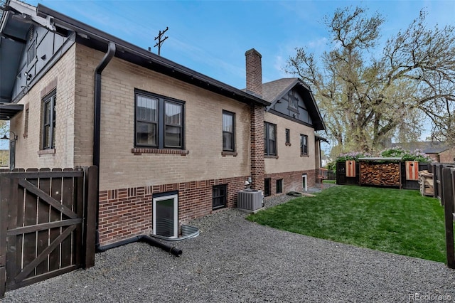 1399 Newton St, Denver, CO 80204 - rear view of property featuring a gate, brick siding, a chimney, and central AC unit