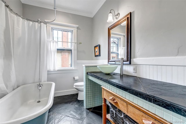 1399 Newton St, Denver, CO 80204 - bathroom featuring a freestanding bath, vanity, a wainscoted wall, toilet, and crown molding