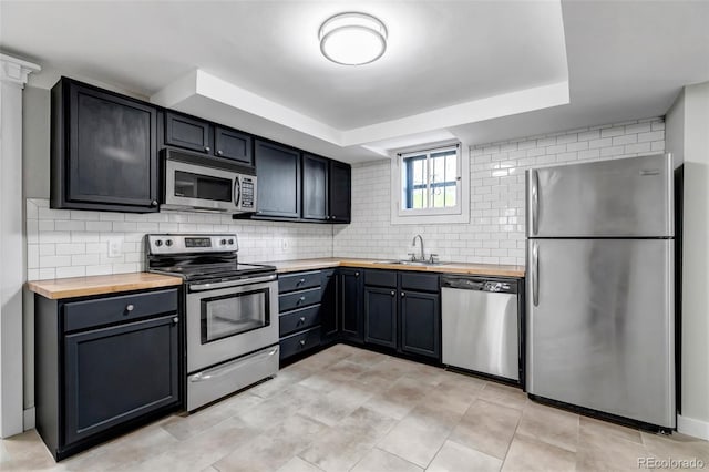 1399 Newton St, Denver, CO 80204 - kitchen with appliances with stainless steel finishes, wooden counters, tasteful backsplash, and a sink