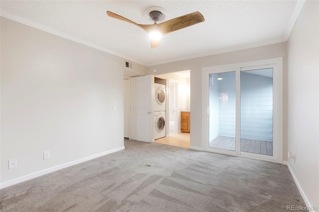 empty room with ceiling fan, light colored carpet, visible vents, ornamental molding, and stacked washer and clothes dryer
