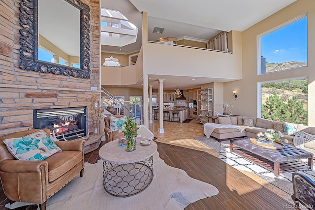 living room featuring ornate columns, a fireplace, and a towering ceiling