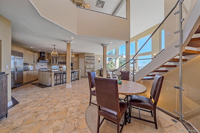 dining space featuring decorative columns, light tile patterned floors, and a towering ceiling