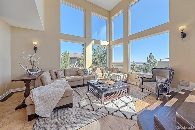 living room featuring tile patterned flooring, a high ceiling, and baseboards