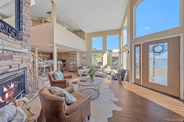 living area with a high ceiling, stairway, a fireplace, and wood finished floors