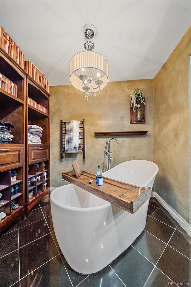 bathroom featuring tile patterned floors, a bathing tub, and an inviting chandelier