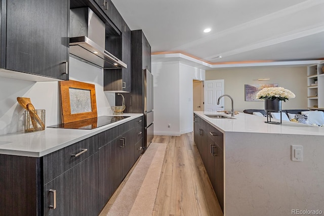 kitchen with wall chimney exhaust hood, a sink, black electric stovetop, and modern cabinets