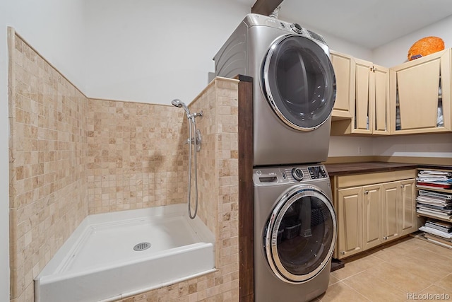 laundry area with stacked washer and dryer, laundry area, and light tile patterned flooring