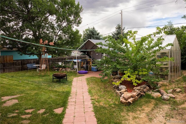 11861 Claude Way, Northglenn, CO 80233 - view of yard featuring a greenhouse, a fire pit, and an outdoor structure