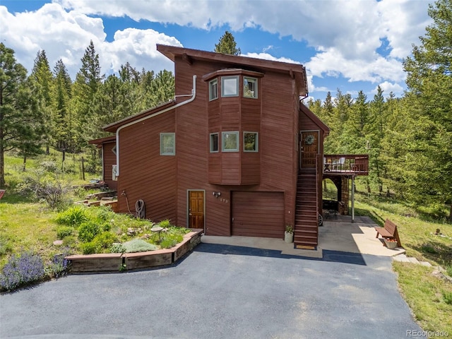 173 Silver Cloud Ln, Boulder, CO 80302 - chalet / cabin with driveway, a garage, a deck, and a view of trees