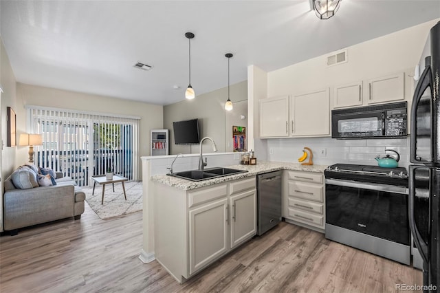 kitchen with a sink, visible vents, black appliances, and a peninsula