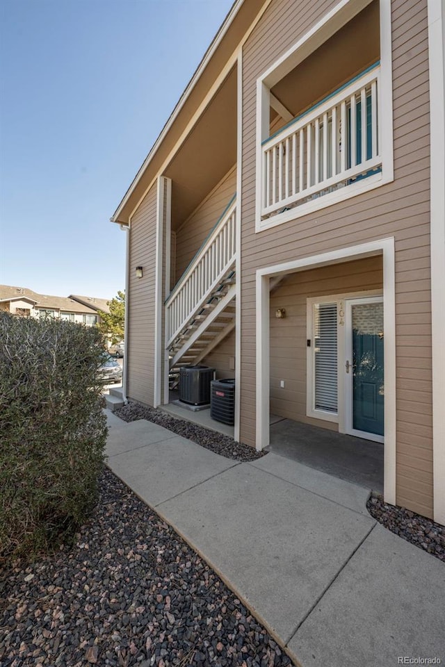 view of side of home with a patio area, cooling unit, and stairs