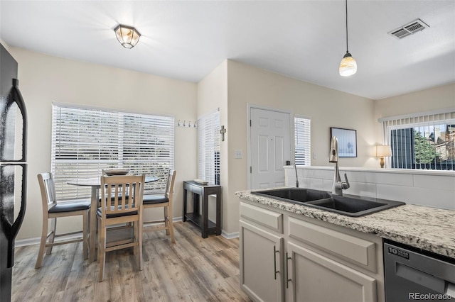 kitchen featuring visible vents, a sink, freestanding refrigerator, light wood-style floors, and dishwashing machine