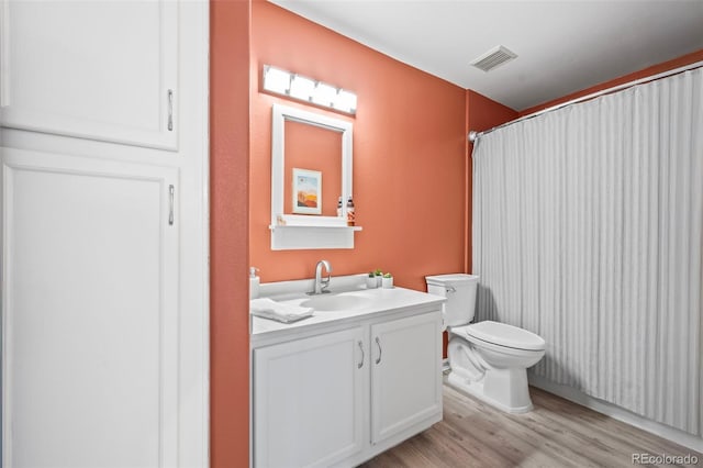 bathroom with vanity, toilet, wood finished floors, and visible vents