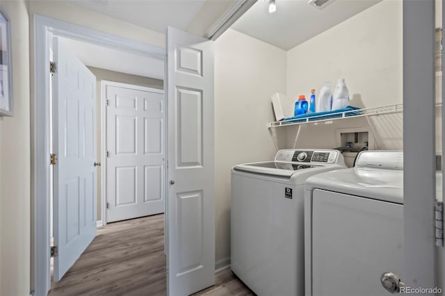 laundry room with laundry area, wood finished floors, separate washer and dryer, and visible vents