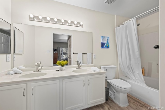 full bath featuring double vanity, wood finished floors, toilet, and a sink