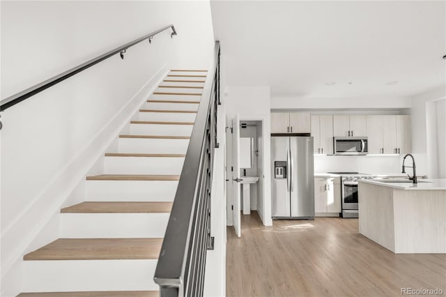 stairway with hardwood / wood-style flooring and sink