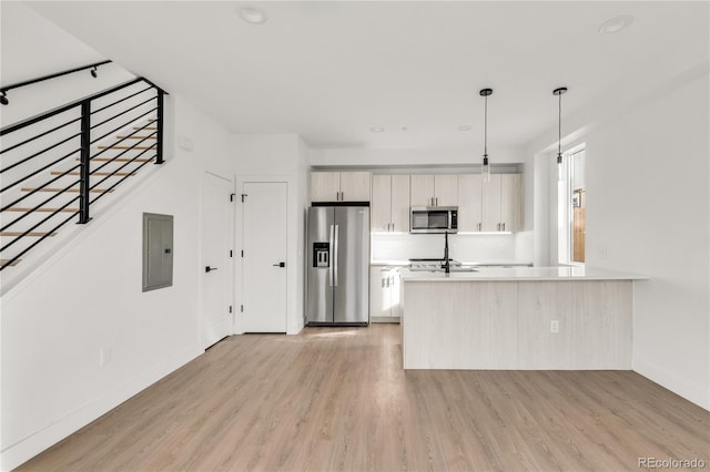 kitchen with electric panel, light hardwood / wood-style flooring, hanging light fixtures, and appliances with stainless steel finishes