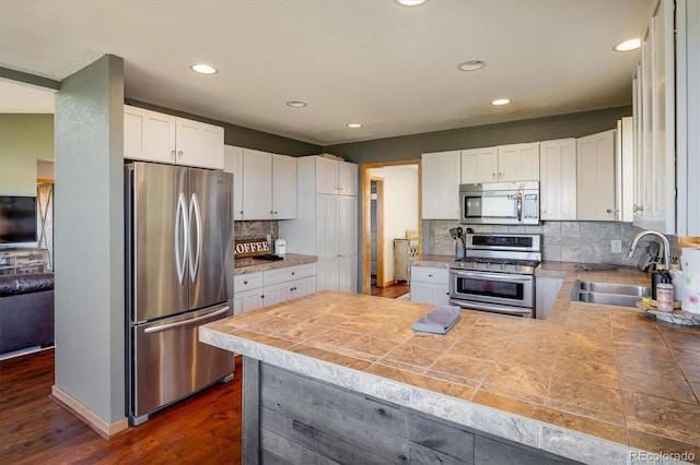 kitchen featuring dark wood-type flooring, sink, appliances with stainless steel finishes, tasteful backsplash, and white cabinetry