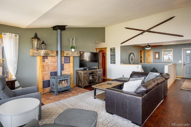 living room with hardwood / wood-style floors, lofted ceiling, ceiling fan, and a wood stove