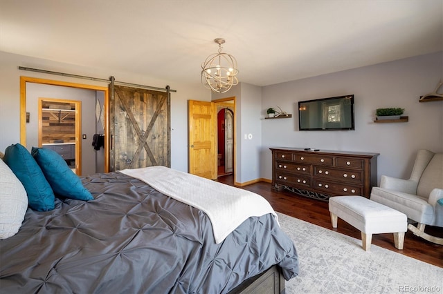 bedroom featuring a walk in closet, a barn door, an inviting chandelier, dark hardwood / wood-style floors, and a closet