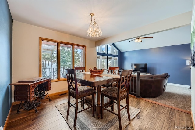 dining room featuring hardwood / wood-style flooring, lofted ceiling, and ceiling fan with notable chandelier