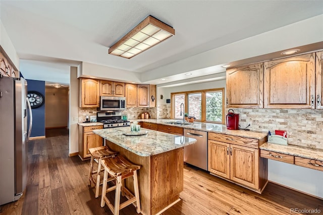 kitchen with a kitchen island, appliances with stainless steel finishes, sink, backsplash, and light hardwood / wood-style floors