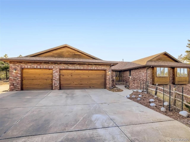 single story home with concrete driveway, brick siding, an attached garage, and fence