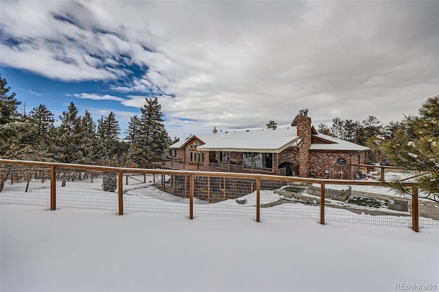 snow covered property featuring a chimney and fence