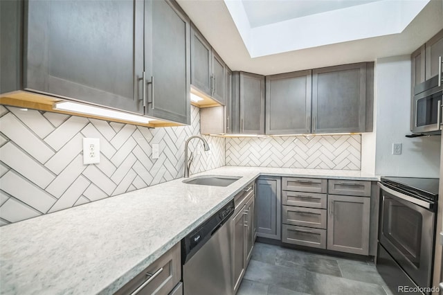 kitchen featuring backsplash, light stone counters, sink, and stainless steel appliances