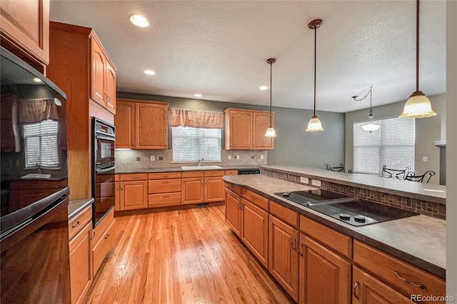 1430 Bluefield Ave, Longmont, CO 80504 - kitchen with a sink, light wood-type flooring, decorative backsplash, black appliances, and hanging light fixtures