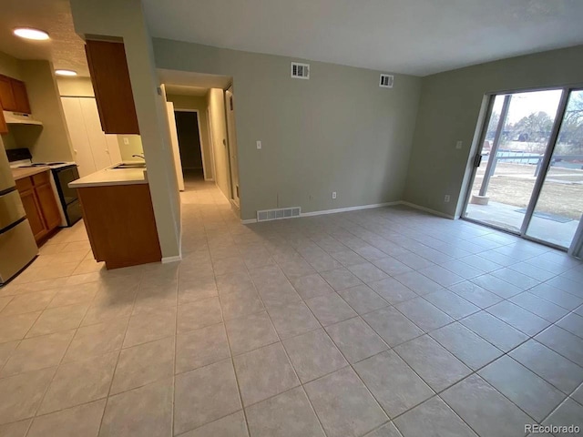100 E Highline Cir Unit 105, Centennial, CO 80122 - kitchen featuring under cabinet range hood, light countertops, range, light tile patterned floors, and open floor plan