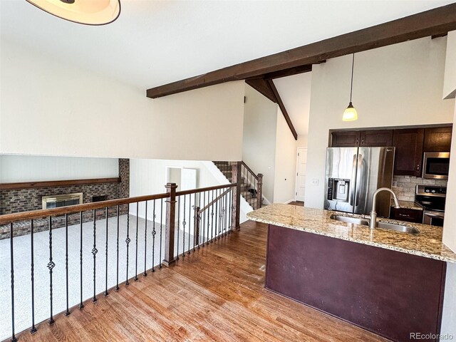 6640 S Heritage Pl W, Centennial, CO 80111 - kitchen with a sink, dark brown cabinetry, beam ceiling, stainless steel appliances, and light wood-style flooring