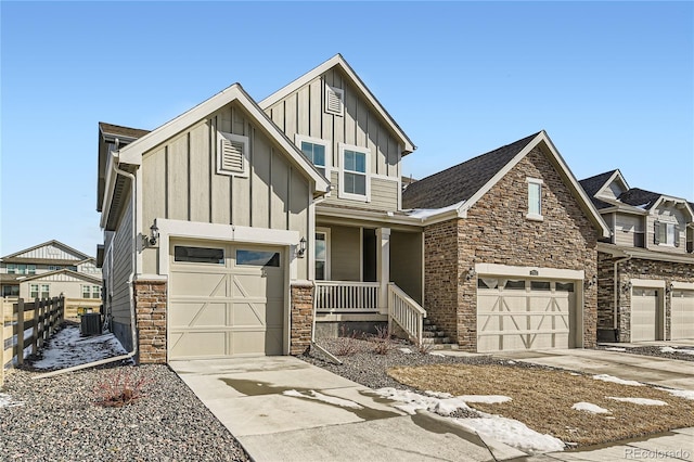 view of front of house with central AC unit, concrete driveway, covered porch, fence, and board and batten siding