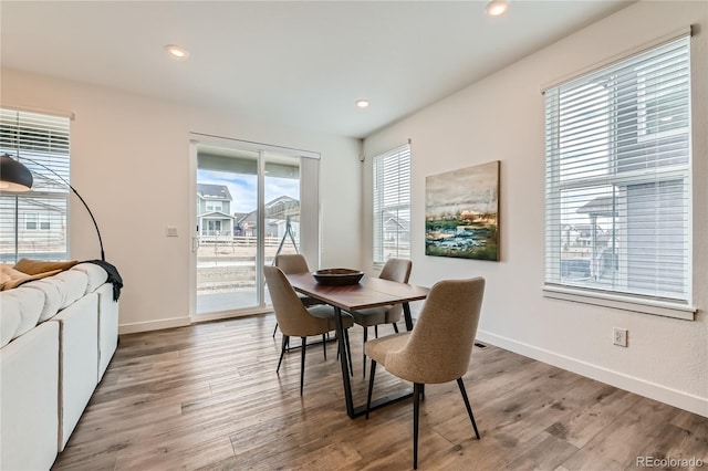 dining space with baseboards, wood finished floors, and recessed lighting