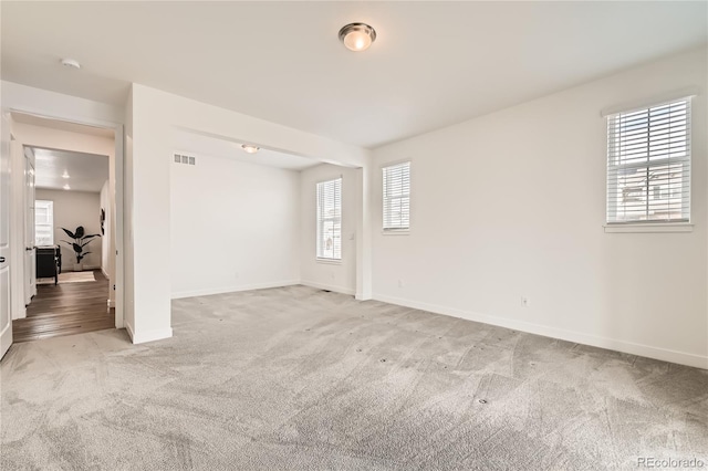 unfurnished room with light carpet, visible vents, and baseboards