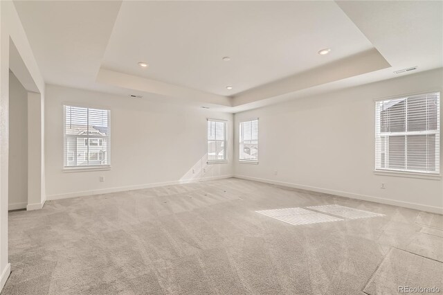 spare room with light carpet, baseboards, a raised ceiling, and recessed lighting