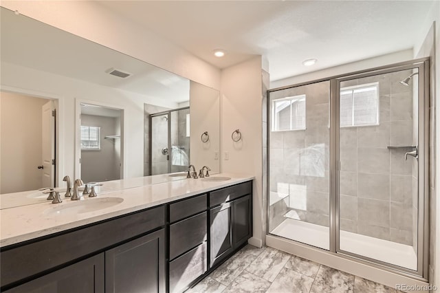 bathroom featuring double vanity, a shower stall, visible vents, and a sink