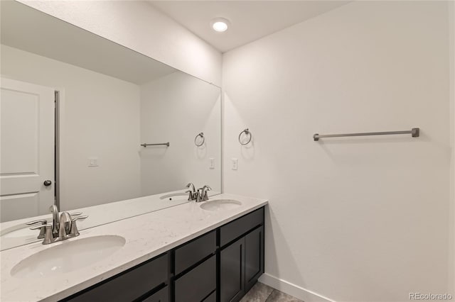 bathroom with a sink, baseboards, and double vanity