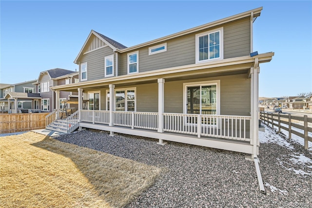 view of front of house with a porch, board and batten siding, fence, and a residential view